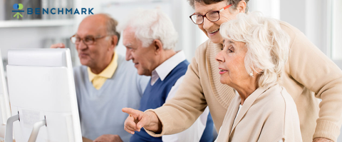 older adults gathered around a computer screen